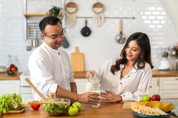 Asian couple nutritious breakfast with fresh milk in kitchen with love and healthy lifestyle,...