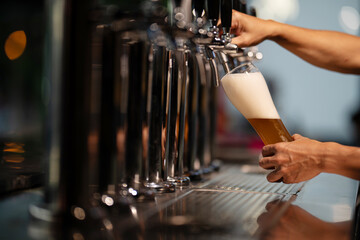 Craft beer is being poured into glasses to be served.