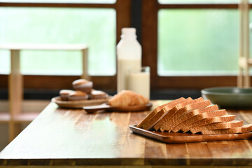 A table with a tray of bread and a bottle of milk. Scene is cozy and inviting