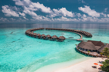 Stunning summer aerial landscape Maldives water villas pristine sea lagoon, sunny blue sky clouds perfect island shore. Beautiful palm trees tropical paradise vacation tourism luxury resort escape