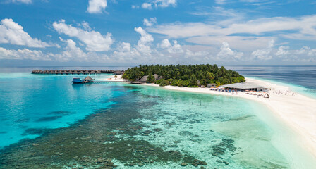Stunning summer aerial landscape Maldives water villas pristine sea lagoon, sunny blue sky clouds perfect island shore. Beautiful palm trees tropical paradise vacation tourism luxury resort escape
