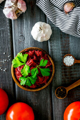 Homemade tomato sause near ingredients - garlic, spices - on dark wooden background top-down