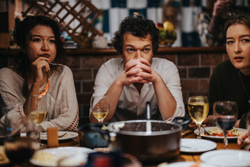 Three individuals seated around a table in a warm, cozy environment enjoying food and drinks.