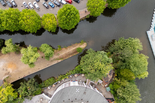 Aerial view of the River Wey snaking past Guildford Rowing Club, with vibrant green trees contrasting against the dark water, Guildford, England, United Kingdom.