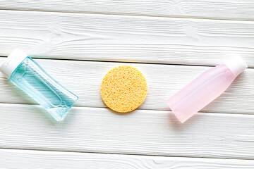 facial tonic, lotion and sponge for face care on white wooden background top view mock up