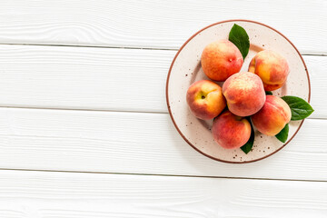 Summer fruits. Ripe red peaches on plate on white wooden table top-down copy space