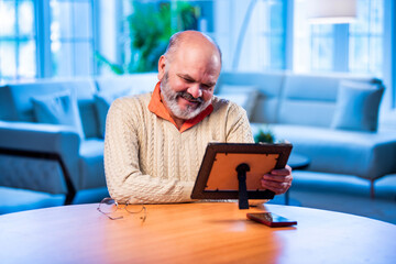 Elderly Indian man holding framed photo with love, lost in memory and emotion