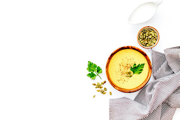 Pumpkin soup on white table top view. Ingredients in bowls. Copy space