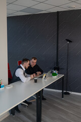 Two Caucasian men sitting at a table and discussing work. 