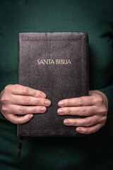 Hands holding front cover of holy bible with reverence. Close view of hands holding the front of...