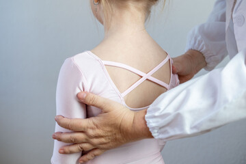 Orthopedist doctor conducts spinal examination child, young girl in ballet leotard shows signs...