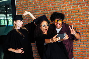 Happy graduates pose for a fun selfie, celebrating success and friendship in graduation gowns....
