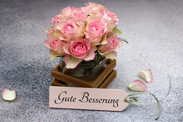 Rosenstrauß mit der Beschriftung Gute Besserung auf einem Schild.