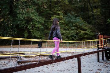 Girl walking on playground bridge maintaining balance and coordination