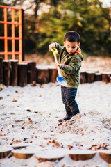 Young child playing with shovel in sandbox at playground