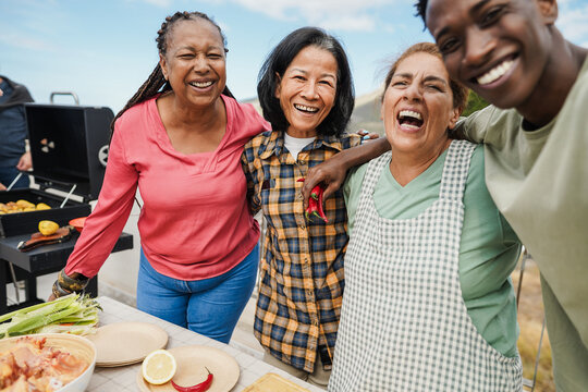 Multi generational people doing selfie during barbecue day on rooftop - Multigeneration group of friends laughing together during summer time - Main focus on asian woman face - Powered by Adobe
