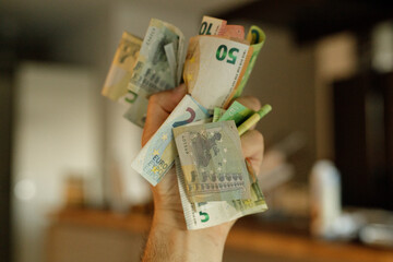 Close-up of a hand holding various Euro banknotes and coins.  Financial concept image.