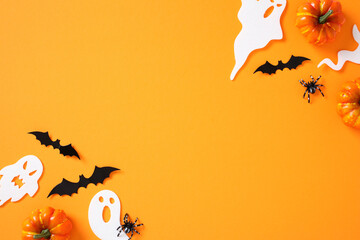 Flat lay Halloween elements: pumpkins, ghosts, bats, spiders, and webs on vibrant orange background