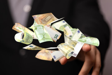 Image of euro banknotes floating in a person's hand, symbolizing wealth and finance.
