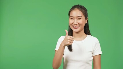 Smiling woman gives a thumbs up on green background