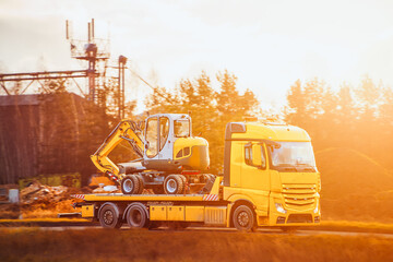 Yellow transport vehicle carrying small excavator