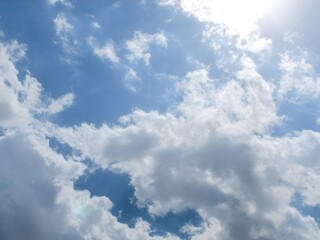 A clear, bright blue sky filled with scattered, fluffy white cumulus clouds on a sunny day.
