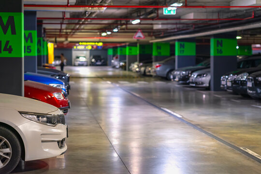 Underground parking, perspective blurred background.. Modern underground parking garage with multiple parked cars and guiding lights. Concept of urban infrastructure, mobility, city convenience