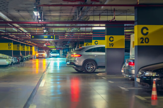 Car Parking Lot in Shopping Mall. Cars entering and exiting underground parking garage, neon lighting. Concept of urban navigation, vehicle flow, modern lifestyle