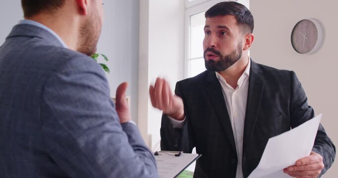 Irritated angry business arguing with colleague holding documents dissatisfied with the terms of contract. Aggressive boss not satisfied with the report or work result from employee. 4k video.