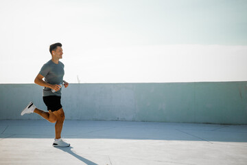 Runner enjoys morning exercise on rooftop under clear sky in urban setting with sunlight...