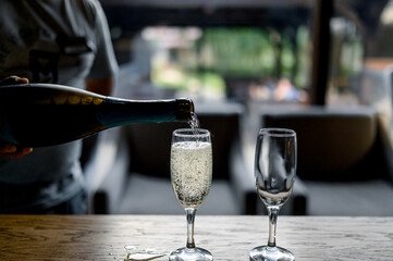 A man pours champagne from a bottle into a glass.