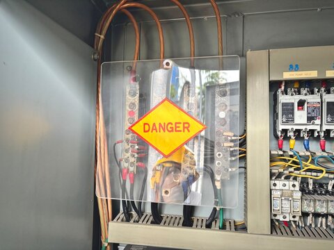 Electrical control panel with a prominent “Danger” warning sign. High voltage components exposed in an industrial power system.