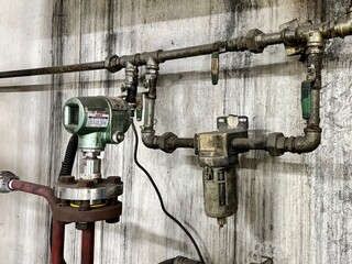 Pressure gauge and sensor setup on an industrial pipeline system, used for monitoring and controlling pressure in manufacturing processes.