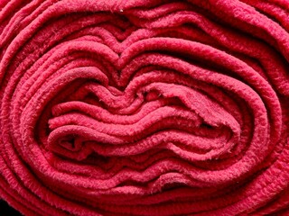 vivid red roll fleece fabric is neatly coiled to display its soft texture and warmth, highlighting...