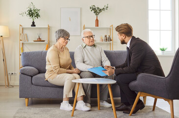 Old couple having negotiations with advisor or real estate agent, discussing investment contract or...
