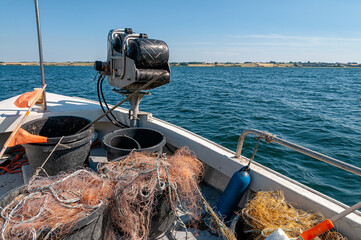 The boat is equipped with fishing nets and containers, ready for fishing in clear blue waters under...