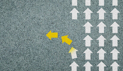 Concept of different business and decisions. Yellow arrow crossing direction, white arrow on asphalt road. With copy space.