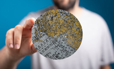 A person holds a circular map of a city, showcasing urban sprawl and infrastructure.