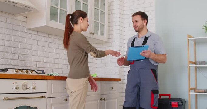 Plumber professional worker and female client deal hand shake after he repairs pipes, fittings, water supply, sanitation, heating systems plumbing, sewage, heat pumps and installations, cleaning