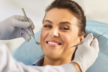 Unrecognizable dentist examining teeth of young woman patient in private clinic, who undergoes...
