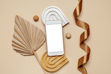 Aesthetic smartphone background with white mockup screen and palm leaves with ribbon top view, brown and beige tone. Smartphone with copy space for branding, invitation, website promotion and design