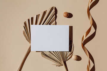 Mockup paper card with palm leaves, ribbon and shadows. Aesthetic paper card in brown tones for invitation, greeting, wedding or branding