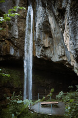 Swiss waterfall in the forest at misty weather