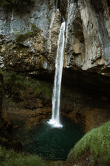 Swiss waterfall in the forest at misty weather