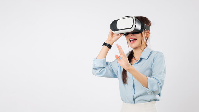 Happy asian woman with vr headset glasses in virtual reality game future touching screen, experiencing technology and using vr application for interaction on white background, isolated studio