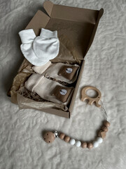 Beige socks with a brown bear, white scratches in a box, a wooden elephant teether and beads next to the bed. The neutral pastel beige color of the accessories. Flatley