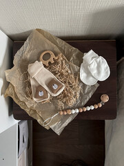 Socks, white scratches, a rodent elephant, beads. A set of accessories and toys for newborns. Fashionable Scandinavian accessories for newborns on a brown bedside table in the room