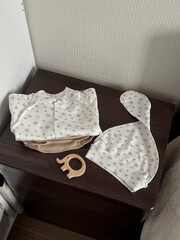 Clothes and accessories for a newborn baby are on the dark brown bedside table. Preparing for the arrival of a child in the family. Top view
