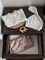 Clothes and accessories for a newborn baby are on the bedside table and in the drawer. Waiting for a miracle. Children's accessories