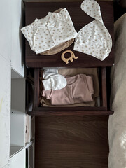 Clothes and accessories for a newborn baby are on the bedside table and in the drawer. Waiting for a miracle. Children's accessories